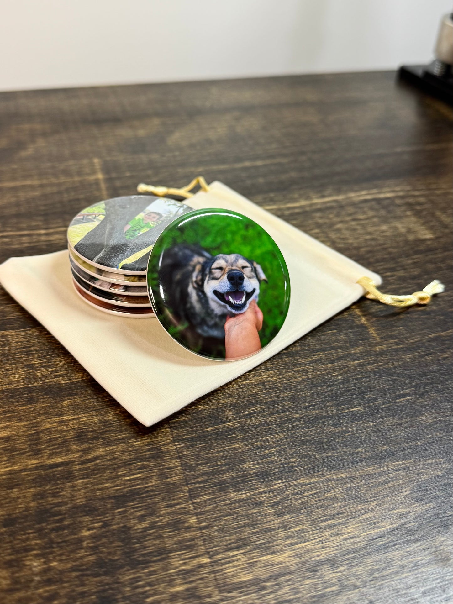 Stack of round photo magnets on a velvet bag. The magnet in front shows a photo of a dog. 