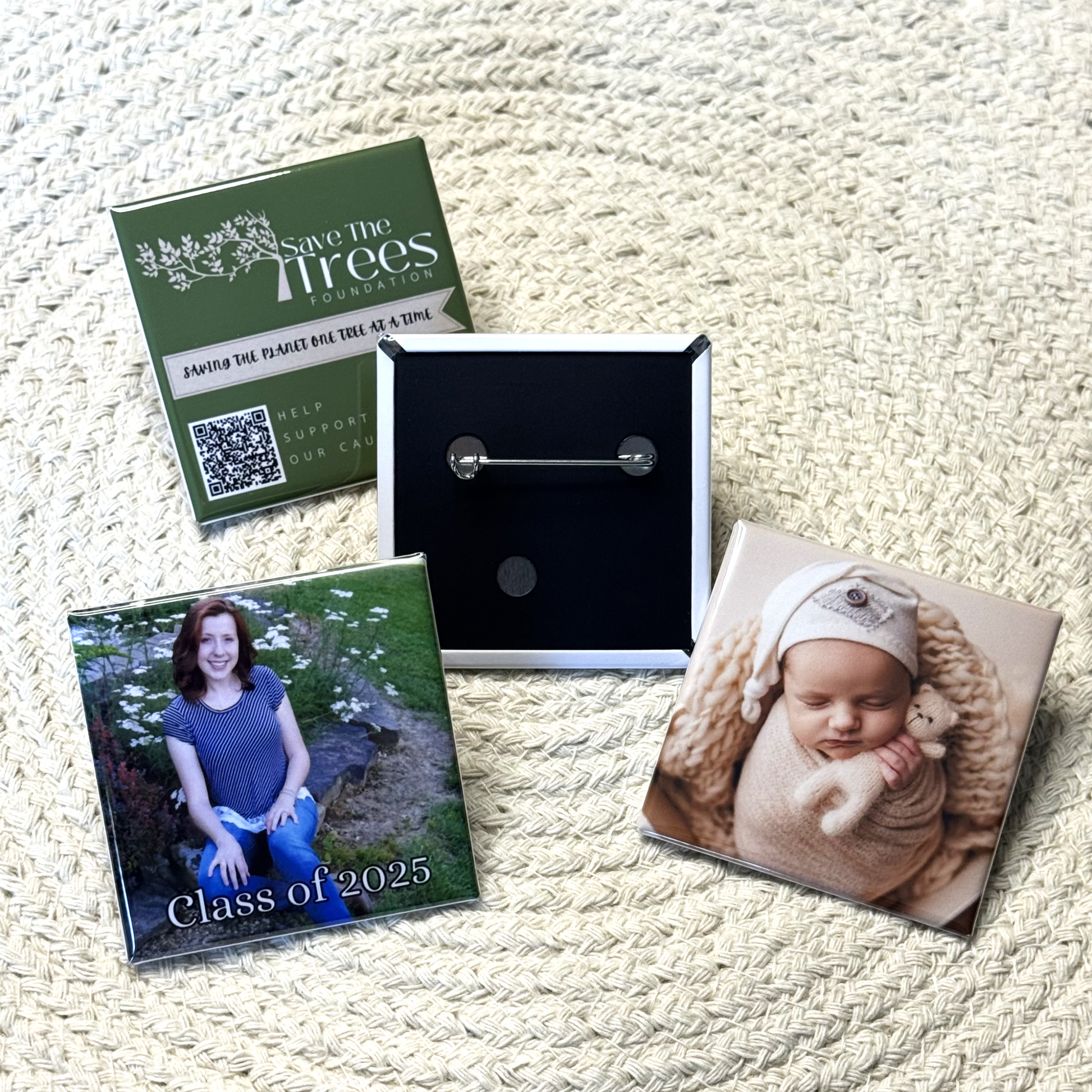 Four custom 2x2 inch square pinback buttons. One is turned around to show the pinback, and the other three show images of a newborn, a graduate and an organization to save the planet. 